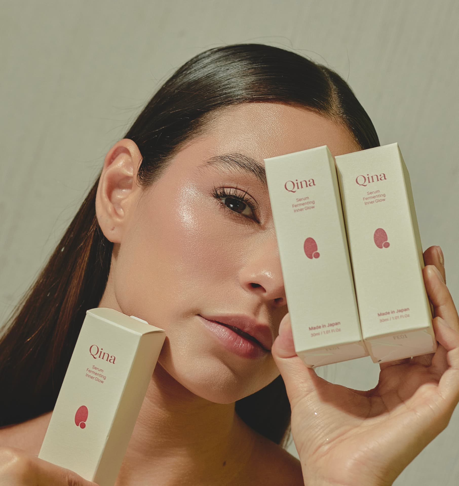 Modelo con estuche de sérum Qina frente a su rostro