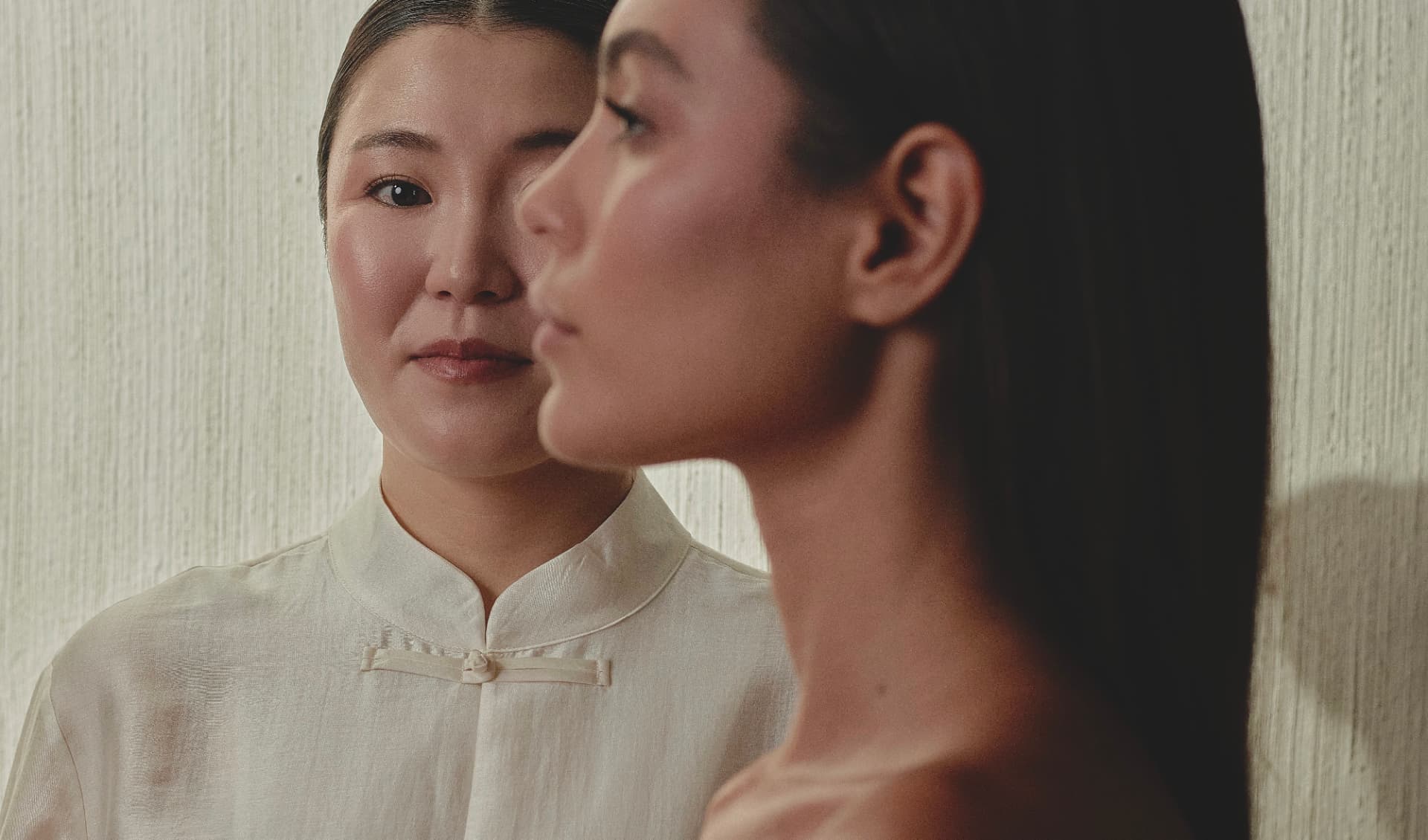Retrato de dos mujeres, una frente al espejo, con vestuario claro