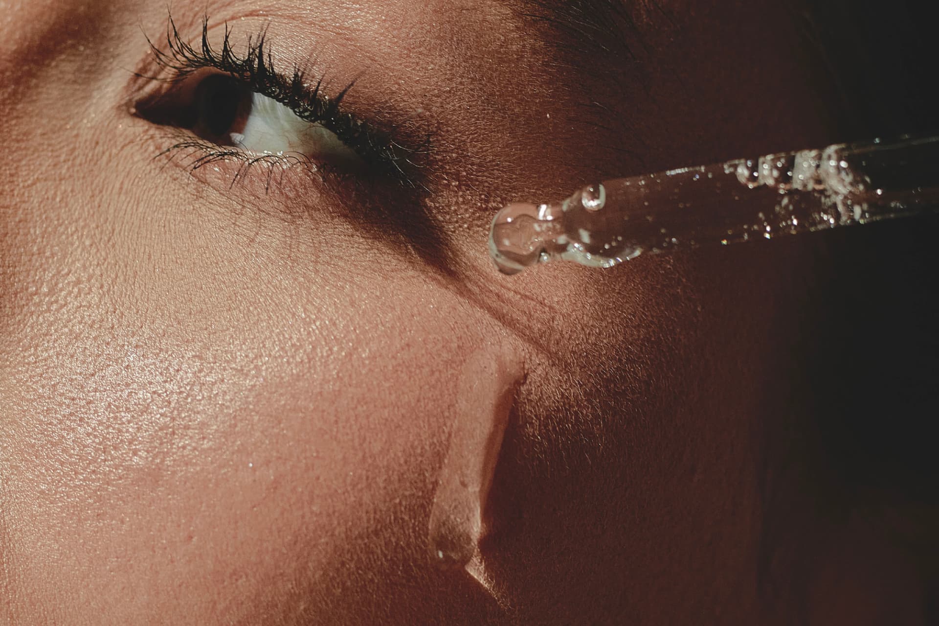 Primer plano de una mirada con una gota del sérum en la mejilla